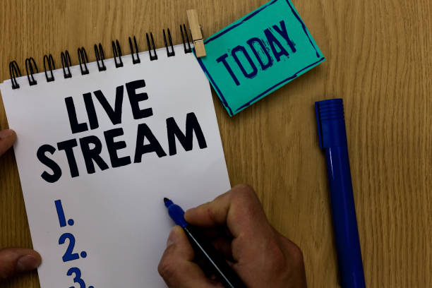 istock Word writing text Live Stream. Business concept for transmit or receive video and audio coverage over Internet Man holding marker notebook clothespin reminder wooden table cup coffee. 1022823988