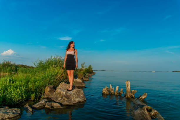 Elegant lady in dress and high heels at the shores if a river