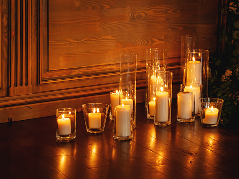 Burning candles in transparent glass vases. Beautiful interior detail for party at night.