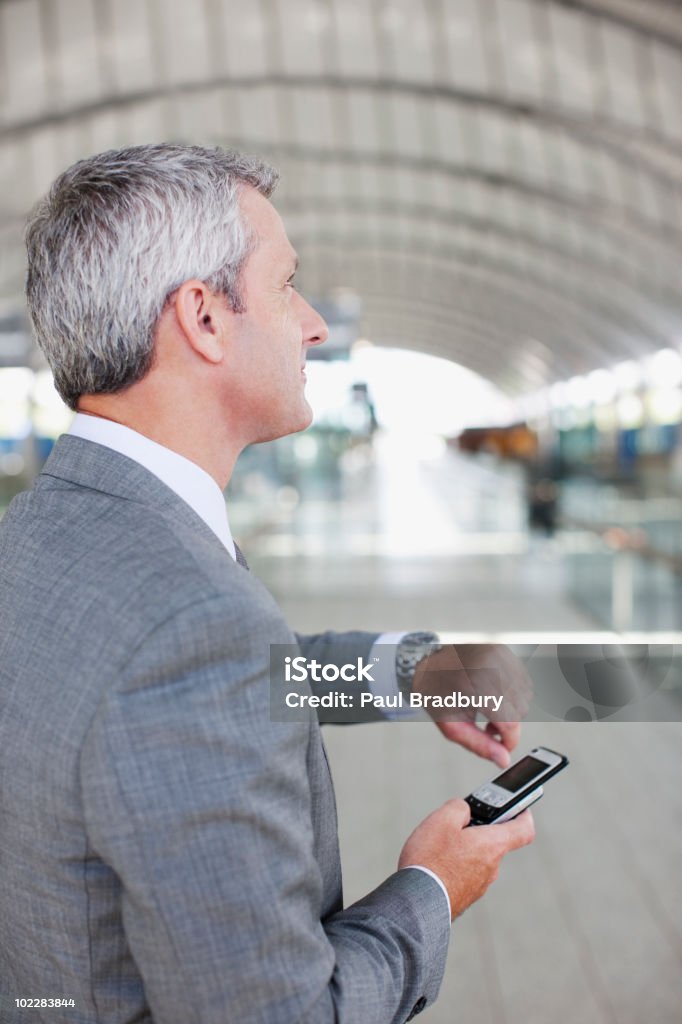 Uomo d'affari con telefono cellulare, controlla il tempo - Foto stock royalty-free di Aspettare