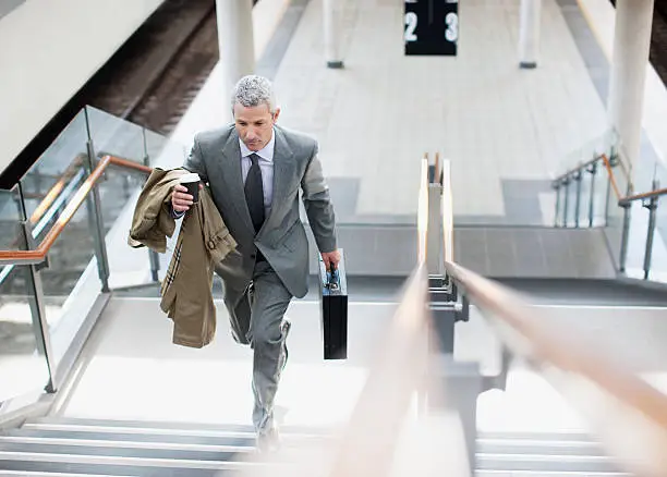 Photo of Businessman walking up stairs in train station