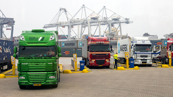 ROTTERDAM, NETHERLANDS - SEP 9, 2013: Container loaded trucks about to leave a shipping terminal in the Port of Rotterdam.