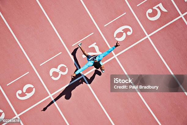 Corredor De Cruzar Alcanzar La Línea De Meta En Pista Foto de stock y más banco de imágenes de Línea de meta