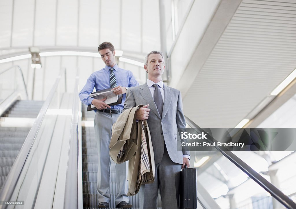 Businessmen descending escalator  Escalator Stock Photo