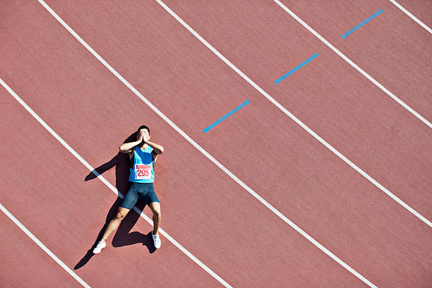 Tired runner laying on track  track and field athlete stock pictures, royalty-free photos & images