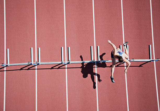 Runner jumping hurdles on track  hurdle stock pictures, royalty-free photos & images