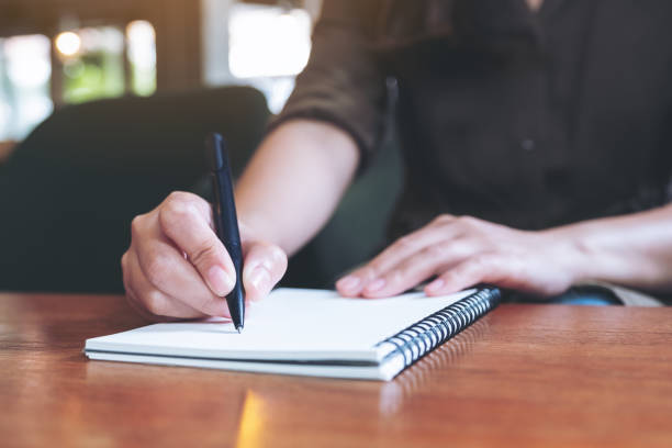 istock Closeup image of a woman writing down on a white blank notebook on wooden table 1022842732