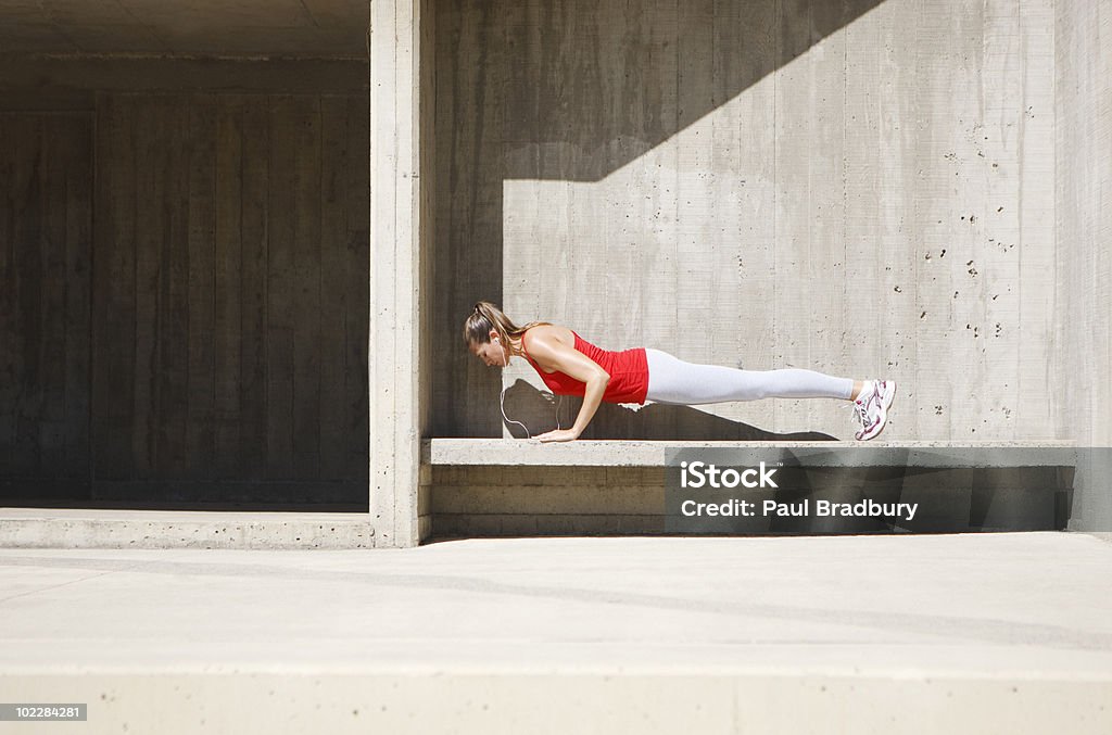 Mujer haciendo flexiones sobre cemento de banco - Foto de stock de Flexiones libre de derechos