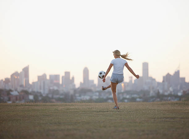 femme frappe ballon de football dans le parc urbain - soccer skill soccer ball kicking photos et images de collection
