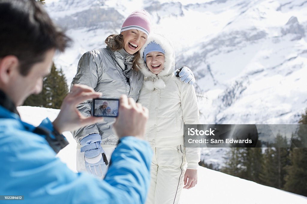 Father taking picture of family in snow  Family Stock Photo