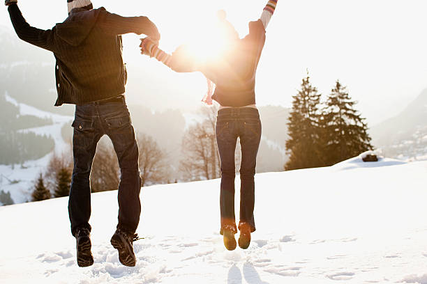paar springen im freien im schnee - couple winter expressing positivity loving stock-fotos und bilder
