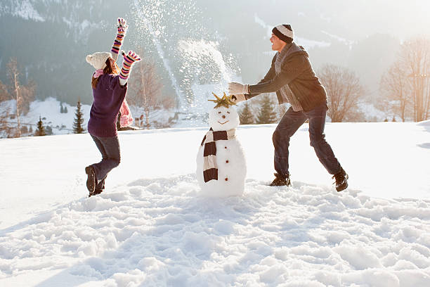 pareja haciendo muñeco de nieve - snowman snow winter fun fotografías e imágenes de stock