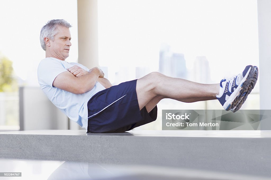 Hombre haciendo sit ups en entorno urbano: - Foto de stock de Abdominales libre de derechos