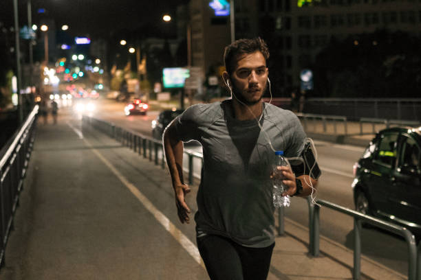 young man jogging through the city at night - night running imagens e fotografias de stock