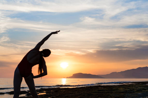 istock young girl practicing yoga on the beach during the sunset 1022851454