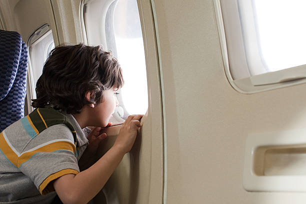 menino olhando pela janela em um avião - airplane window indoors looking through window - fotografias e filmes do acervo