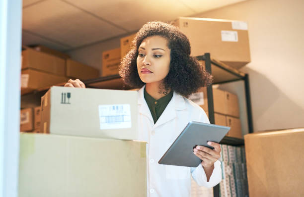 Ensuring that stock arrives on time every time Shot of a young woman using a digital tablet while doing inventory in the storeroom of a pharmacy medical supplies stock pictures, royalty-free photos & images