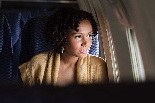 weibliche flugzeug passagier schaut aus dem fenster - color image people air vehicle airplane stock-fotos und bilder