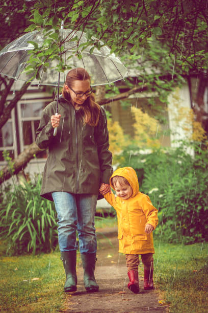 istock Mother and son in raincoats walking in rain 1022873432