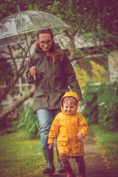 istock Mother and son in raincoats walking in rain 1022873436