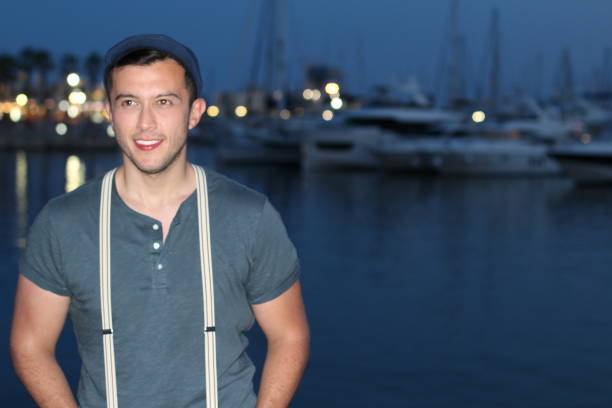 Trendy man with suspenders and hat smiling and laughing.