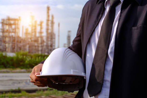 istock The engineer is holding a helmet with large industry background. 1022878078