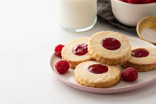Christmas cookies. Linzer cookies with raspberry jam on white table background. Traditional Austrian biscuits filled. Top view.