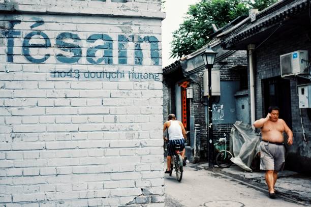 résidents de la hutong no43 avec un grand panneau sur le mur - graffiti paintings men walking photos et images de collection
