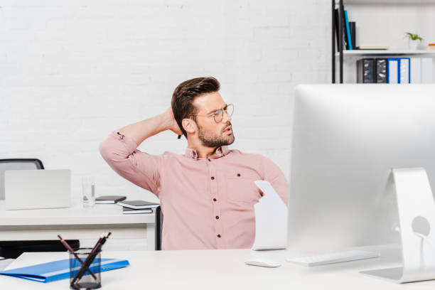 istock overworked young businessman stretching at modern office 1022898718