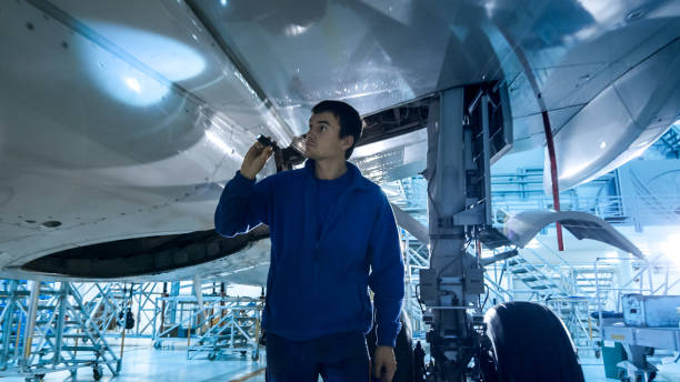 istock Aircraft maintenance mechanic with a flash light inspects plane fuselage in a hangar. 1022905048