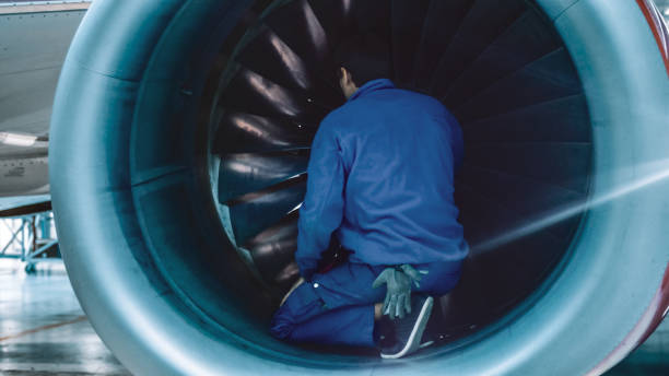 aircraft maintenance mechanic with a flash light inspects plane turbine blades in a hangar. - fixed wing aircraft imagens e fotografias de stock