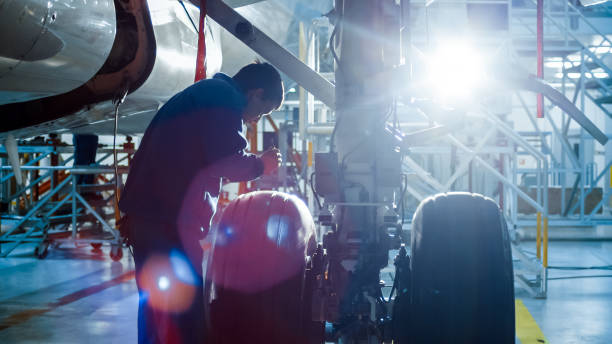 istock Aircraft maintenance mechanic with a flash light inspects plane chassis in a hangar. 1022905092
