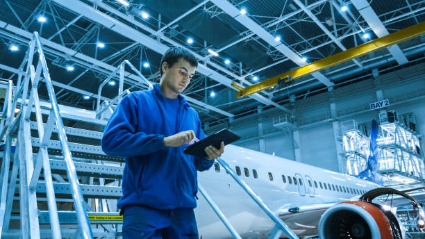 istock Aircraft maintenance mechanic in blue uniform is going down the stairs while using tablet in a hangar. 1022905124