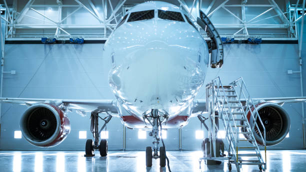 colpo a terra di un aereo nuovo di zecca in piedi in un hangar per la manutenzione degli aeromobili. la porta dell'aereo è aperta e la scala si trova accanto ad essa. - hangar foto e immagini stock