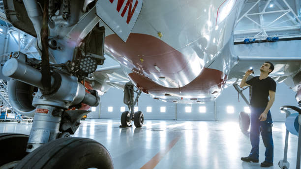 istock In a Hangar Aircraft Maintenance Engineer/ Technician/ Mechanic Visually Inspects Airplane's Chassis and Body/Fuselage walking Under It. 1022905146