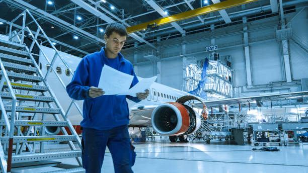 istock Aircraft maintenance mechanic in blue uniform is going down the stairs while reading papers in a hangar. 1022905150