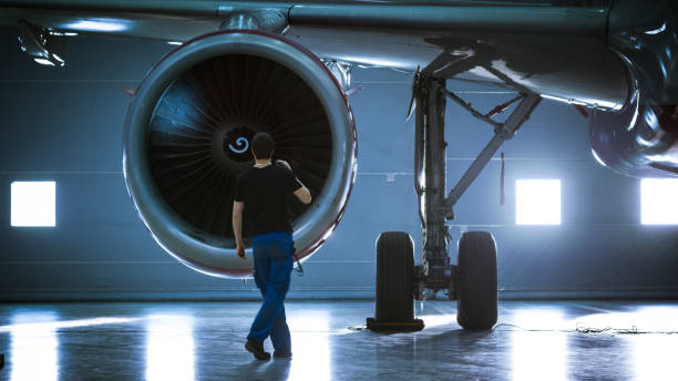 istock In a Hangar Aircraft Maintenance Engineer/ Technician/ Mechanic Inspects with a Flashlight Airplane's Jet Engine. 1022905204