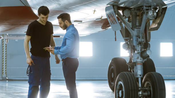 istock In a Hangar Aircraft Maintenance Engineer Shows  Technical Data on Tablet Computer to Airplane Technician. They Stand Near Clean Brand New Plane. 1022905214