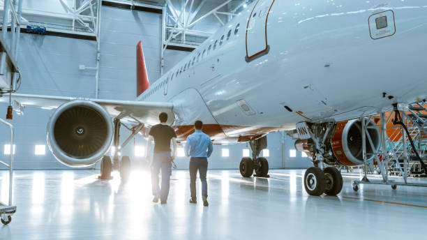 istock In a Hangar Aircraft Maintenance Engineer Shows  Technical Data on Tablet Computer to Airplane Technician. They Walk Alongside Clean Brand New Plane. 1022905236