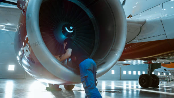 istock In a Hangar Aircraft Maintenance Engineer/ Technician/ Mechanic Inspects with a Flashlight Airplane's Jet Engine. 1022905258