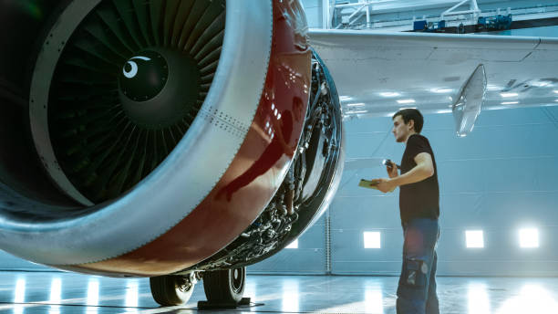 istock In a Hangar Aircraft Maintenance Young Engineer/ Technician/ Mechanic With Tablet Computer Inspects Airplane Jet Engine. He Opens Engine Hatch and Examines Insides with a Flashlight. 1022905280