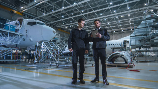 istock Team of Aircraft Maintenance Mechanics Moving through Hangar. Holding Tablet Computer 1022905504