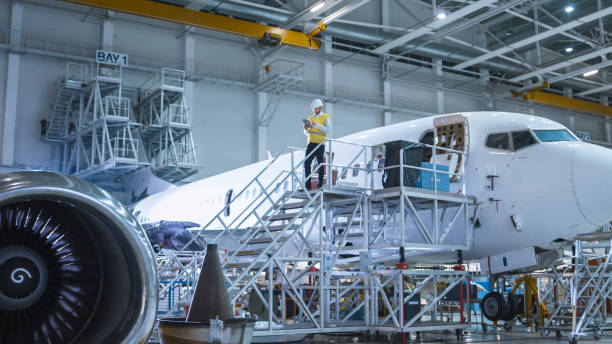 istock Engineer in Safety Vest Standing next to Airplane in Hangar 1022905530