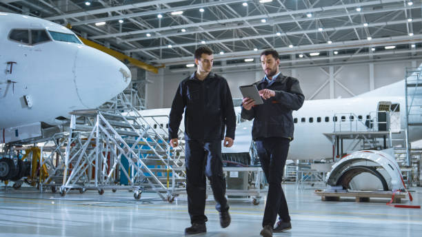 istock Team of Aircraft Maintenance Mechanics Moving through Hangar. Holding Tablet Computer 1022905532