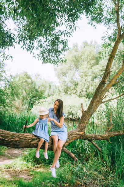 istock stylish mother and daughter sitting on tree trunk together 1022910436