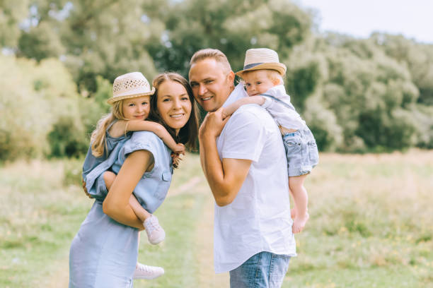 istock parents piggybacking children in straw hats on summer feild 1022910610