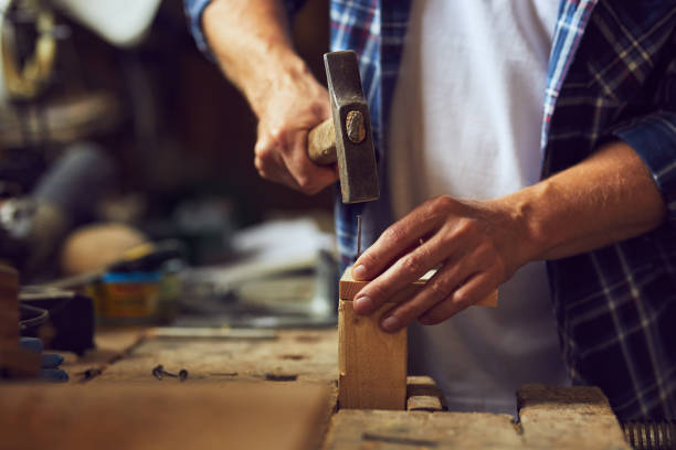 istock Carpenter hammering a nail into wooden plank 1022910992