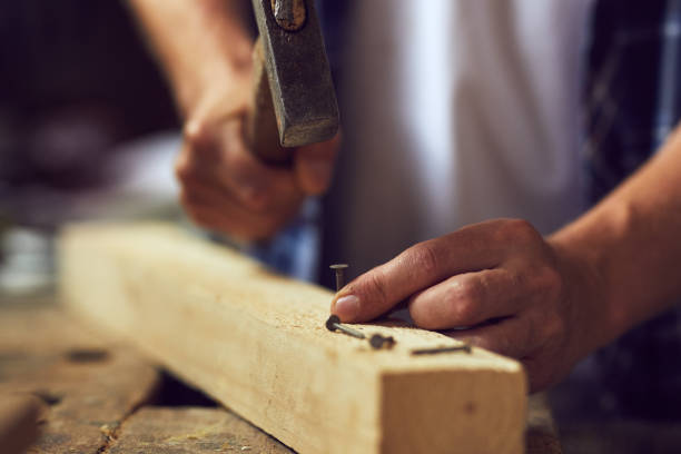 istock Carpenter hammering a nail into wooden plank in his workshop 1022911062