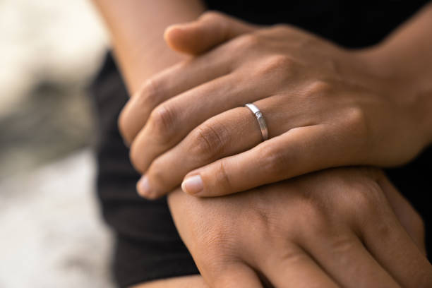 istock silver white engagement ring on fiancees hand - romantic proposal on beach 1022924794