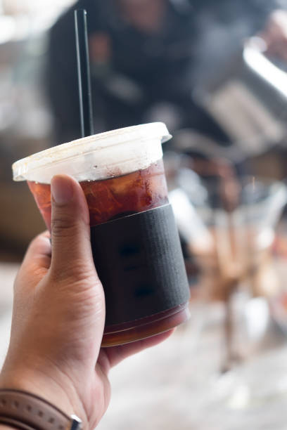 istock Ice Americano coffee in plastic cup on young hand 1022929580